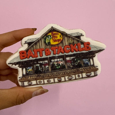 Cookie of a store front  of Bass pro Shops with 'Bait & Tackle' text held by a hand against a pink background