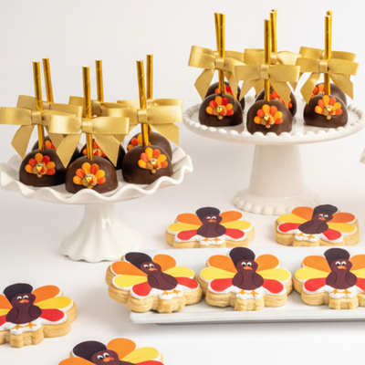 Dessert display with cookies shaped like turkeys and chocolate-covered treats on sticks.