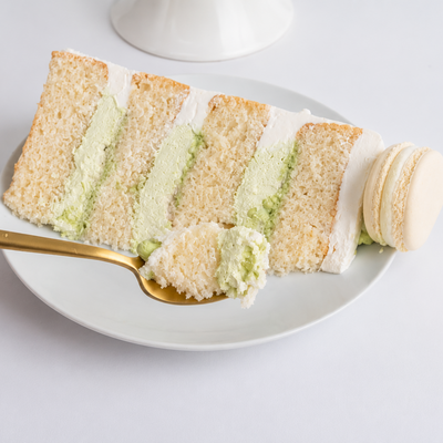 Slice of matcha layered cake with a hand holding a gold spoon