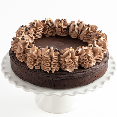 Chocolate cake with brown frosting on a white cake stand