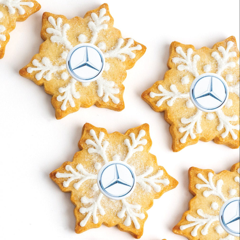 Snowflake-shaped cookies with Mercedes-Benz logo on a white background
