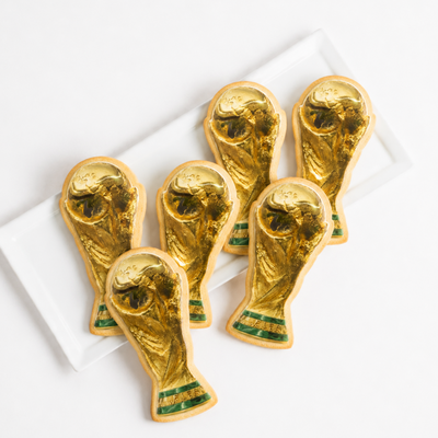 Gold World Cup trophy cookies on a white plate